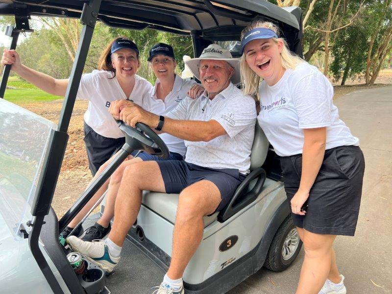 Photo of 2 golfers on golf buggy with 2 Bravehearts employees