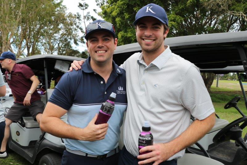 2 male golfers in front of buggies