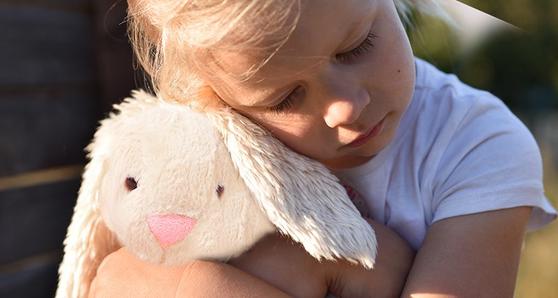 sad little girl holding soft toy bunny
