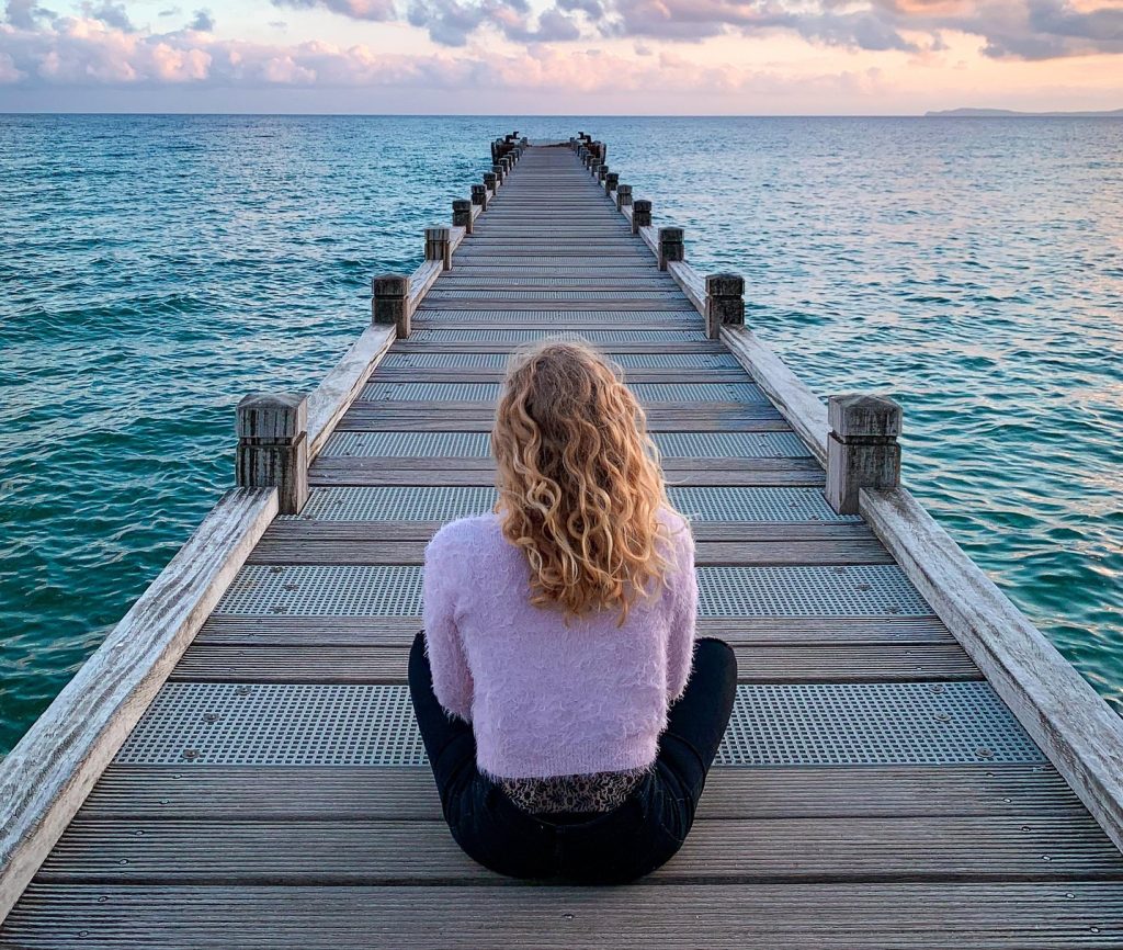 Woman sitting on dock looking out to sea