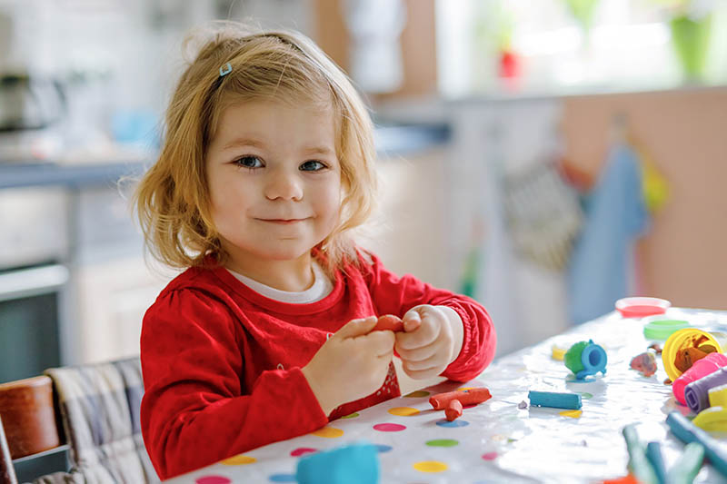 Adorable Cute Little Toddler Girl With Colorful Clay. Healthy Baby Playing And Creating Toys From Play Dough. Small Kid Molding Modeling Clay And Learning